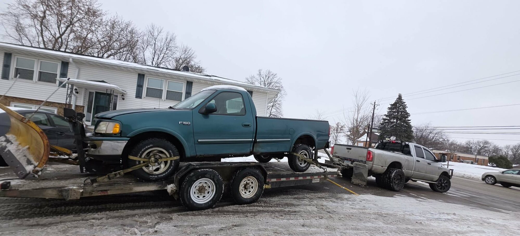 Ford F-150 strapped on a tilt trailer for winter vehicle transport