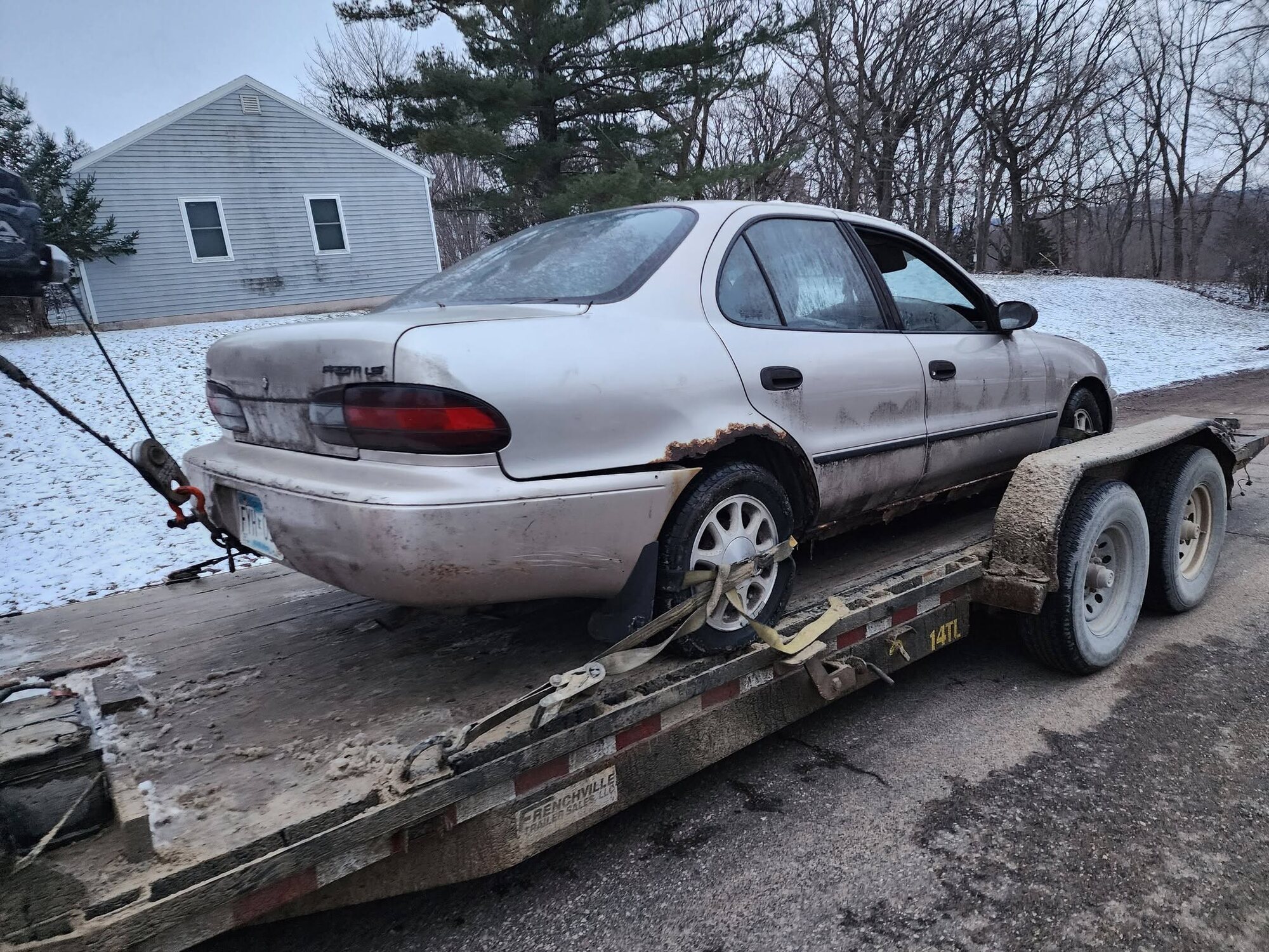 Junk car winched onto a tilt trailer for recovery